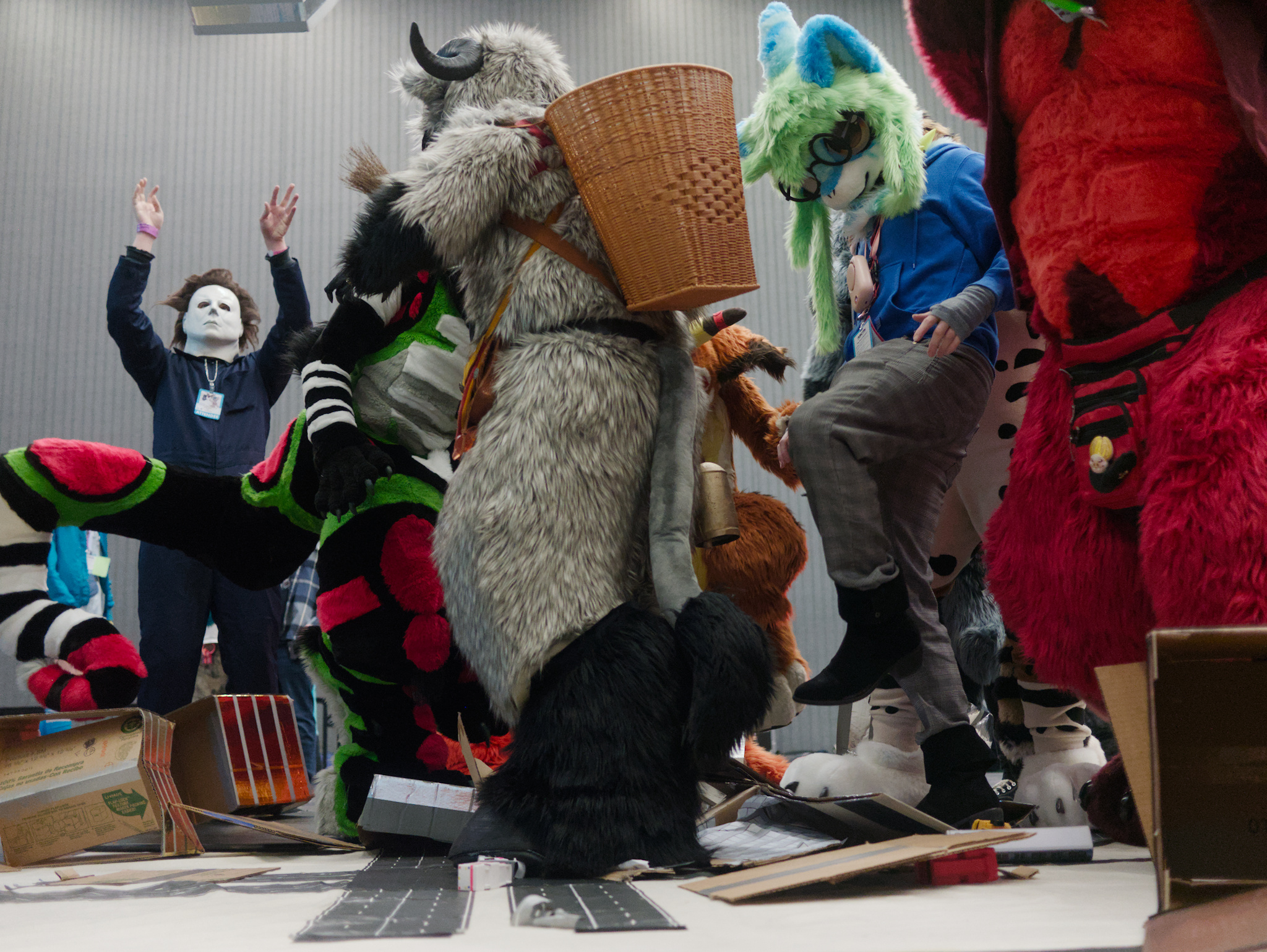 a photo of fursuiters stomping on a micro city made of cardboard boxes. michael myers stands in the background, hands raised